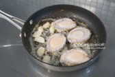 마늘 향이 올라오면 전복을 올려주세요. 이 때 칼집을 넣은 부분을 먼저 구워주면 모양이 휘어지지 않고 골고루 익습니다.