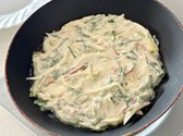 프라이팬에 오일을 넉넉히 두르고 부추전 반죽을 얇게 펼쳐 올립니다. 부추전이 윗부분에 구멍이 생길 때까지 자주 뒤집지 말고 기다리세요. 기름이 부족하지 않도록 추가하며 부쳐줍니다.