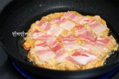 반죽이 약간 익으면 대패삼겹살을 토핑으로 얹고 뒤집어 구워줍니다. 돼지기름이 나오므로 처음부터 기름을 많이 둘 필요는 없습니다.